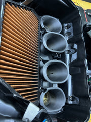 Close-up of a motorcycle air filter with brown pleated design and metal components.