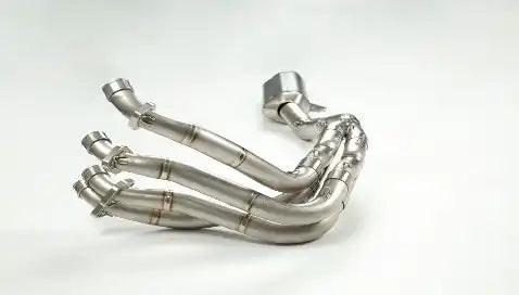 Curved stainless steel exhaust header with multiple connecting pipes.